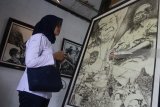 Pengunjung melihat lukisan berjudul Lintas Agama Gus Dur karya pelukis Sudibyo dalam pameran Lukisan bertajuk 