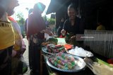 Pedagang melayani pembeli di pasar jajanan tradisional di Desa Wisiata Kemiren, Banyuwangi, Jawa Timur, Minggu (4/2). Pasar yang menjual makanan tradisional suku Osing yang diadakan setiap hari minggu itu, pembeli harus menggunakan kepeng atau kepingan uang kuno untuk bertransaksi. Antara jatim/Budi Candra Setya/zk/18.