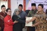 Ketua Komisi Pemilihan Umum (KPU) Jawa Timur Eko Sasmito (kanan) menyerahkan berkas pengesahan penetapan pada Ketua tim pemenangan pasangan Saifullah Yusuf-Emil Elestianto Dardak, Hikmah Bafaqih (ketiga kiri) ketika Rapat Pleno Terbuka Penetapan Pasangan Calon dalam Pemilihan Gubernur dan Wakil Gubernur 2018 Jawa Timur 2018 di Kantor KPU Jawa Timur, Surabaya, Senin (12/2). KPU Jawa Timur secara resmi menetapkan dua pasangan calon Gubenur dan Wakil Gubernur Jawa Timur yakni pasangan Saifullah Yusuf-Puti Guntur Soekarno dan pasangan Khofifah Indar Parawansa-Emil Elestianto Dardak dalam Pemilihan Gubernur pada 27 Juni mendatang. Antara Jatim/M Risyal Hidayat/zk/18