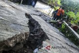 Warga melintasi kawasan yang mengalami kerusakan akibat pergerakan tanah di Desa Cimanintin, Jatinunggal, Kabupaten Sumedang, Jawa Barat, Selasa (27/2). Akibat peristiwa tersebut sebanyak 64 rumah rusak dan 187 warga sudah dievakuasi. ANTARA JABAR/Agvi Firdaus/agr/18