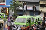 Dua supir angkot berdiri di atas mobil angkotnya dan memberi hormat saat dihukum polisi di jalan Juanda, Kota Bogor, Jawa Barat, Rabu (21/2). Anggota Polresta Bogor Kota memberi hukuman pada dua supir angkot tersebut karena melanggar aturan dengan berhenti sembarang tempat dan menimbulkan kemacetan. ANTARA JABAR/Arif Firmansyah/agr/18.