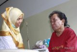 Tenaga Kerja Wanita (TKW) asal Tambaksari Surabaya, Ida Susilawati (kanan) berbincang dengan tenaga medis di Puskesmas Entikong, Kabupaten Sanggau, Kalbar, Kamis (8/2). Ida Susilawati (54) yang terserang stroke saat hendak berangkat ke Brunei Darussalam tersebut, telah dirawat di Puskesmas Entikong sejak Kamis (21/12/17) dan hingga kini belum dijemput oleh keluarganya karena keterbatasan biaya. ANTARA FOTO/Agus Alfian/jhw/18