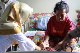 Tenaga Kerja Wanita (TKW) asal Tambaksari Surabaya, Ida Susilawati (kanan) berbincang dengan tenaga medis di Puskesmas Entikong, Kabupaten Sanggau, Kalbar, Kamis (8/2). Ida Susilawati (54) yang terserang stroke saat hendak berangkat ke Brunei Darussalam tersebut, telah dirawat di Puskesmas Entikong sejak Kamis (21/12/17) dan hingga kini belum dijemput oleh keluarganya karena keterbatasan biaya. ANTARA FOTO/Agus Alfian/jhw/18