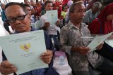 Sejumlah warga memperlihatkan sertifikat tanah program Pendaftaran Tanah Sistematis Lengkap (PTSL) usai diserahterimakan di Kantor Kelurahan Burengan, Kota Kediri, Jawa Timur, Kamis (8/2). Penyerahan sertifikat tanah secara massal tersebut guna mendukung pencapaian target pemerintah tujuh juta sertifikat bidang tanah pada tahun 2018 melalui program PTSL dengan 1.570.000 sertifikat di antaranya berlokasi di Jawa Timur. Antara Jatim/Prasetia Fauzani/zk/18