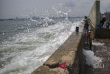 Warga diterpa ombak air laut saat beraktivitas di Kawasan Pelabuhan Perikanan Samudera Nizam Zachman, Jakarta, Kamis (1/2). Badan Meteorologi Klimatologi dan Geofisika (BMKG) menghimbau masyarakat yang berada di pesisir pantai agar mewaspadai peningkatan air pasang yang dipicu fenomena alam Gerhana Super Blue Blood Moon. ANTARA FOTO/Galih Pradipta/wdy/2018.