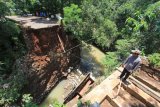 Warga berada di sekitar jembatan Cikaroya yang putus di desa Gumulung Lebak, Beber, Cirebon, Jawa Barat, Minggu (25/2). Jembatan penghubung dua kecamatan yaitu kecamatan Beber dan Greged tersebut putus akibat terjangan air saat banjir terjadi pada Sabtu (24/2) lalu.
