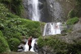 Pengunjung berada di area air terjun Dolo, Kediri, Jawa Timur, Rabu (21/3). Air terjun setinggi 125 meter di lereng gunung Wilis itu pada hari biasa sepi pengunjung karena hanya bisa ditempuh dengan berjalan kaki menuruni ribuan anak tangga. Antara Jatim/Prasetia Fauzani/zk/18