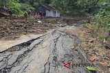 Warga melewati jalan yang tertutup material tanah akibat pergerakan tanah, di desa Randusari, Cibeureum, Kuningan, Jawa Barat, Selasa (27/2). Selain merusak rumah warga, pergerakan tanah di desa tersebut juga membuat jalan amblas dan tertutup material longsor sehingga tidak dapat dilalui kendaraan. ANTARA JABAR/Dedhez Anggara/agr/18.