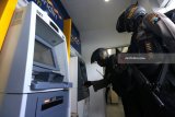 Polisi memeriksa mesin Anjungan Tunai Mandiri (ATM) di Bank Mandiri, Jalan Indrapura, Surabaya, Jawa Timur, Selasa (20/3). Peningkatan patroli dengan melakukan pemeriksaan mesin ATM di sejumlah bank yang dilakukan oleh Unit Raimas Sat Sabhara Polrestabes Surabaya itu untuk mengantisipasi kejahatan 'skimming'. Antara Jatim/Didik Suhartono/zk/18