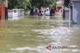 Warga melintasi genangan banjir yang merendam desa Wanakaya, Gunung Jati, Cirebon, Jawa Barat, Senin (12/3). Akibat hujan deras sejak dua hari lalu membuat banjir meluas hingga tujuh kecamatan di Cirebon. ANTARA JABAR/Dedhez Anggara/agr/18.