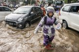 Warga berjalan melintasi genangan banjir di kawasan Cikadut, Bandung, Jawa Barat, Minggu (11/3). Sejumlah ruas jalan raya di Kota Bandung kerap mengalami banjir akibat intensitas curah hujan yang tinggi serta sistem drainase yang kurang baik. ANTARA JABAR/Novrian Arbi/agr/18