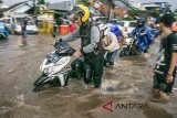 Pengendara mendorong sepeda motor untuk melintasi genangan banjir di kawasan Cikadut, Bandung, Jawa Barat, Minggu (11/3). Sejumlah ruas jalan raya di Kota Bandung kerap mengalami banjir akibat intensitas curah hujan yang tinggi serta sistem drainase yang kurang baik. ANTARA JABAR/Novrian Arbi/agr/18