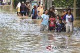 Warga menerobos banjir yang merendam desa Gunungjati, Cirebon, Jawa Barat, Minggu (11/3). Banjir akibat jebolnya tanggul sungai tersebut merendam ratusan rumah warga dan jalur alterntif penghubung Cirebon - Indramayu sehingga mengakibatkan kemacetan. ANTARA JABAR/Dedhez Anggara/agr/18.