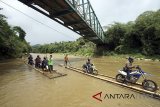 Sejumlah pengendara roda dua memanfaatkan jasa perahu rakit untuk menyeberangi Sungai Cisadane di Rumpin, Bogor, Jawa Barat, Senin (12/3). Akibat rusaknya jembatan yang menghubungkan akses jalan utama Rumpin-Ciseeng, sejumlah warga memanfaatkan jasa penyeberangan sepeda motor dengan perahu rakit atau getek dengan tarif Rp10.000 untuk sekali melintas. ANTARA JABAR/Yulius Satria Wijaya/agr/18.