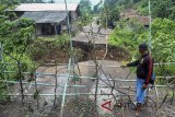 Warga melihat jembatan yang putus akibat longsor di Desa Mekarsari, Cikalong Kulon, Kabupaten Cianjur, Jawa Barat, Sabtu (10/3). Meluapnya sungai Cipinang akibat intensitas hujan yang tinggi di wilayah Cianjur pada Jum'at (9/3) sore, mengakibatkan jembatan putus dan menutup akses warga menuju jalan utama Cianjur-Jonggol. ANTARA JABAR/Arif Firmansyah/agr/18