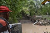 Warga berada di dekat jembatan yang roboh akibat diterjang banjir di Desa Gandri, Kecamatan Pangkur, Kabupaten Ngawi, Jawa Timur, Senin (12/3). Akibat robohnya jembatan tersebut warga harus melewati jalur lain dengan selisih jarak sekitar empat kilometer lebih jauh. Antara Jatim/Foto/Siswowidodo/zk/18