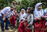 Calon Gubernur Jawa Barat nomor urut empat Deddy berbincang dengan siswi sekolah dasar saat melakukan kampanye di Kampung Adat Cireundeu, Cimahi, Jawa Barat, Jumat (23/3). Dalam kampanyenya, Deddy Mizwar berharap Masyarakat Adat Cirendeu dapat mempertahankan kebudayaannya dan berpesan agar dapat memilih pemimpin yang tepat saat pilkada pada Juni mendatang. ANTARA JABAR/Raisan Al Farisi/agr/18.