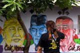 Warga mengamati mural potret para tokoh seniman ludruk di dinding sebuah rumah saat digelar Festival Manunggaling Dwi Budoyo dan peresmian Kampung Parikan di Surabaya, Jawa Timur, Kamis (1/3). Kampung tersebut diharapkan menjadi salah satu kampung budaya dan tempat pendidikan non formal bagi masyarakat. Antara JatimZabur Karuru/18