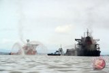 Dua kapal tugboat memadamkan sisa api yang masih membakar dek kapal kargo MV Ever Judger di perairan Teluk Balikpapan, Kalimantan Timur, Sabtu (31/3/2018). Akibat terbakarnya pipa minyak bawah air Balikpapan-Penajam Paser Utara, mengakibatkan satu kapal kargo MV Ever Judger dan dua kapal nelayan terbakar serta menewaskan dua nelayan. (ANTARA/Sheravim) 