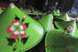 Perajin menyelesaikan pengecatan topi caping di Desa Gadingan, Sliyeg, Indramayu, Jawa Barat, Jumat (9/3). Hasil kerajinan topi caping itu dijual Rp15.000 per buah. ANTARA JABAR/ Dedhez Anggara/agr/18.