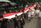 Umat Hindu berjalan sambil membentangkan kain berwarna Merah Putih menuju ke tempat berlangsungnya upacara Melasti di Surabaya, Jawa Timur, Minggu (11/3). Upacara rangkaian Hari Raya Nyepi yang diikuti ribuan umat Hindu di Surabaya tersebut bertujuan untuk membersihkan diri dan jiwa dari segala bentuk perbuatan buruk. Antara Jatim/Didik Suhartono/zk/18