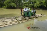 Pelajar menggunakan rakit bambu untuk menyeberang Sungai Ciputrahaji di Desa Sukasari, Kabupaten Ciamis, Jawa Barat, Rabu (7/3). Mereka terpaksa menggunakan rakit bambu karena tidak adanya jembatan penghubung Desa Sukasari dengan Desa Sindangrasa. ANTARA JABAR/Adeng Bustomi/agr/18.