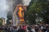 Wisatawan dan warga menyaksikan pembakaran peti jenazah berbentuk sapi yang berisi jenazah keluarga Puri (kerajaan) Ubud, Anak Agung Niang Agung dalam upacara Ngaben akbar di Desa Peliatan, Ubud, Jumat (2/3). Ritual kremasi berskala besar tersebut melibatkan ribuan warga dan wisatawan untuk penghormatan terakhir. Antaranews Bali/Nyoman Budhiana/2018.