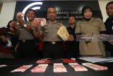 Polisi menunjukkan sejumlah tersangka dan barang bukti uang palsu saat ungkap kasus peredaran uang palsu di Polrestabes Surabaya, Jawa Timur, Selasa (27/3). Polrestabes Surabaya menangkap 11 tersangka atas kasus dugaan mengedarkan uang palsu dan mengamankan barang bukti 916 lembar uang palsu pecahan Rp100.000 dan 28 lembar uang palsu Dollar Singapura pecahan SGD10.000. Antara Jatim/Didik Suhartono/zk/18