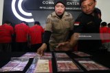 Polisi menunjukkan sejumlah tersangka dan barang bukti uang palsu saat ungkap kasus peredaran uang palsu di Polrestabes Surabaya, Jawa Timur, Selasa (27/3). Polrestabes Surabaya menangkap 11 tersangka atas kasus dugaan mengedarkan uang palsu dan mengamankan barang bukti 916 lembar uang palsu pecahan Rp100.000 dan 28 lembar uang palsu Dollar Singapura pecahan SGD10.000. Antara Jatim/Didik Suhartono/zk/18