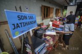 Seorang guru mengamankan arsip sekolah yang terdampak banjir bandang di SDN 165 Jatihandap, Bandung, Jawa Barat, Rabu (21/3). Akibat banjir bandang yang melanda kawasan Jatihandap sejak Selasa (20/3) sore, Guru SDN 165 Jatihandap meliburkan sekolah karena masih banyak fasilitas yang terendam lumpur. ANTARA JABAR/Raisan Al Farisi/agr/18