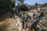 Warga bersama Anggota TNI memperbaiki tanggul sungai Cironggeng yang jebol di Cingised, Bandung, Jawa Barat, Sabtu (10/3). Tanggul yang jebol akibat intensitas hujan tinggi pada Kamis (8/3) malam tersebut mengakibatkan sekitar 70 rumah warga terendam air yang bercampur dengan lumpur. ANTARA JABAR/Raisan Al Farisi/agr/18