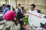 Petugas melayani warga yang tengah mengurus kepesertaan BPJS Kesehatan di Bandung, Jawa Barat, Senin (5/3). BPJS Kesehatan menargetkan kepesertaan Badan Usaha terpenuhi melalui strategi canvassing dan penegakan kepatuhan, untuk mewujudkan Universal Health Coverage pada 2019 mendatang. ANTARA JABAR/Raisan Al Farisi/agr/18