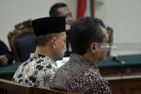 Terdakwa Kepala Dinas Lingkungan Hidup Pemkab Nganjuk nonaktif Harjanto (kanan) dan Kabag Umum RSUD Kabupaten Nganjuk nonaktif Mokhammad Bisri (kiri) menjalani sidang putusan kasus suap kepada Bupati Nganjuk di Pengadilan Tindak Pidana Korupsi (tipikor) Surabaya di Juanda, Sidoarjo, Jawa Timur, Senin (12/3). Majelis hakim menjatuhkan vonis pidana penjara masing masing selama dua tahun dan denda Rp200 Juta Subsider 6 bulan dalam kasus suap kepada Bupati Nganjuk 2013-2018 Taufiqurrahman terkait perekrutan dan pengelolaan ASN/PNS di Kabupaten Nganjuk pada 2017. Antara Jatim/Umarul Faruq/zk/18