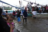 Warga menaiki perahu di bibir pantai Desa Jangkar, Jangkar, Situbondo, Jawa Timur, Jumat (2/3). Ribuan warga memadati pinggir pantai dan menyewa perahu untuk melihat langsung ikan paus jenis sperma yang terdampar. Antara Jatim/Seno/zk/18.