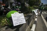 Pengemudi Gojek menuliskan keluhan yang ditempelkan pada helm di kawasan Tugu Pal Putih, DI Yogyakarta, Jumat (23/3). Ratusan pengemudi Gojek melakukan aksi mogok massal dengan menuliskan keluhan pada helm di sepanjang jalan Margo Utomo kawasan Tugu Pal Putih sebagai bentuk protes kebijakan manajemen PT Gojek Indonesia yang menurunkan tarif minimal dari Rp8.000 menjadi Rp4.000. ANTARA FOTO/Hendra Nurdiyansyah/aww/18.