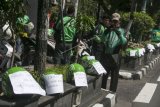 Pengemudi Gojek menuliskan keluhan yang ditempelkan pada helm di kawasan Tugu Pal Putih, DI Yogyakarta, Jumat (23/3). Ratusan pengemudi Gojek melakukan aksi mogok massal dengan menuliskan keluhan pada helm di sepanjang jalan Margo Utomo kawasan Tugu Pal Putih sebagai bentuk protes kebijakan manajemen PT Gojek Indonesia yang menurunkan tarif minimal dari Rp8.000 menjadi Rp4.000. ANTARA FOTO/Hendra Nurdiyansyah/aww/18.