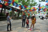 Sejumlah pengunjung berfoto di bawah hiasan payung warna-warni di kawasan Tugu Khatulistiwa Pontianak, Kalbar, Rabu (21/3). Hiasan ratusan payung tersebut meramaikan peringatan Pesona Titik Kulminasi Matahari yang rutin terjadi setiap tanggal 21-23 Maret dan 21-23 September. ANTARA FOTO/Jessica Helena Wuysang/18
