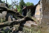 Warga memotong pohon mangga yang roboh menghancurkan benteng rumah karena angin puting beliung di Desa Wonorejo, Kediri, Jawa Timur, Senin (2/4). Angin kencang yang disertai dengan hujan lebat di wilayah itu merusak puluhan rumah warga. Antara jatim/Prasetia Fauzani/zk/18