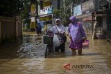 Warga melintasi wilayah yang terendam banjir di Dayeuhkolot, Kabupaten Bandung, Jawa Barat, Sabtu (21/4). Beberapa wilayah Kabupaten Bandung di bantaran Sungai Citarum kembali terendam banjir dengan ketinggian 30 hingga 70 cm akibat curah hujan yang tinggi sejak Jumat (20/4). ANTARA JABAR/Raisan Al Farisi/agr/18