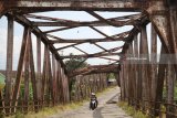 Pengendara sepeda motor melintas di atas jembatan lama Kertosono yang konstruksinya telah miring di Kertosono, Nganjuk, Jawa Timur, Selasa (3/4). Jembatan peninggalan Belanda penghubung Kabupaten Nganjuk dengan Kabupaten Kediri itu dibuka paksa oleh warga setelah sebulannya ditutup total dan dipasang garis polisi karena hampir roboh. Antara jatim/Prasetia Fauzani/zk/18