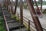 Pengendara sepeda motor melintas di atas jembatan lama Kertosono yang konstruksinya telah miring di Kertosono, Nganjuk, Jawa Timur, Selasa (3/4). Jembatan peninggalan Belanda penghubung Kabupaten Nganjuk dengan Kabupaten Kediri itu dibuka paksa oleh warga setelah sebulannya ditutup total dan dipasang garis polisi karena hampir roboh. Antara jatim/Prasetia Fauzani/zk/18