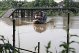 Warga menyeberangi sungai Brantas menggunakan jasa perahu penyeberangan dengan latar belakang jembatan Mrican yang runtuh di Desa Jongbiru, Kediri, Jawa Timur, Senin (23/4). Warga berharap jembatan penghubung antar Kabupaten/Kota Kediri yang runtuh setahun lalu tersebut segera dibangun kembali karena merupakan saranan transportasi vital wilayah setempat. Antara Jatim/Prasetia Fauzani/zk/18
