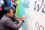 Menteri Pemuda dan Olahraga Imam Nahrawi (kanan) turut membuat mural saat bhakti sosial yang digelar Pengurus Pusat Fatayat Nahdlatul Ulama (NU) di Desa Batu Merah, Ambon, Maluku, Jumat (27/4). Bhakti sosial dalam bentuk pengecatan rumah warga dan pembuatan mural tersebut merupakan bagian dari rangkaian Konferensi Besar (Konbes) Fatayat NU ke-16, di Ambon, 26-29 April 2018. (ANTARA FOTO/izaac mulyawan) 