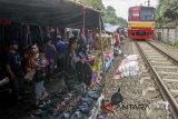 Kereta Commuterline jurusan Jakarta-Stasiun Nambo melintas di pasar kaget pinggir rel kereta di kawasan Citeureup, Bogor, Jawa Barat, Jumat (6/4). Meskipun berbahaya dan berpotensi mengakibatkan kecelakaan serta mengganggu lalu lintas kereta, para pedagang tetap menjajakan dagangannya di pasar tersebut. ANTARA JABAR/Yulius Satria Wijaya/agr/18.