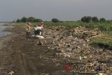 Warga mengais sampah yang menumpuk di pantai Singaraja, Indramayu, Jawa Barat, Minggu (15/4). Berbagai jenis sampah seperti sampah plastik dan kayu yang terdampar akibat dampak musim angin barat tersebut mengakibatkan aktivitas warga dan wisatawan terganggu. ANTARA JABAR/Dedhez Anggara/agr/18.