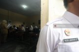 Petugas Lembaga Pembinaan Khusus Anak (LPKA) Kelas 1 Blitar berjaga didepan ruang ujian saat berlangsung Ujian Nasional Berbasis Komputer (UNBK) di salah satu SMA swasta di Kota Blitar, Jawa Timur, Senin (9/4). Sebanyak 16 siswa binaan tersebut mengikuti UNBK hari pertama dengan mata ujian Bahasa Indonesia dan terbagi menjadi dua sesi, karena keterbatasan perangkat komputer di lokasi ujian. Antara jatim/Irfan Anshori/zk/18