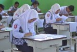 Sejumlah pelajar SMP Negeri 18 Palu mengerjakan soal ujian nasional dengan skema ujian nasional berbasis kertas dan pensil (UNKP) di SMP Negeri 18 Palu, Kelurahan Mamboro, Palu Utara, Sulawesi Tengah, Senin (23/4). Sebagian sekolah SMP di Kota Palu belum dapat melaksanakan ujian nasional berbasis komputer (UNBK) karena keterbatasan fasilitas terutama komputer.  (ANTARA FOTO/Mohamad Hamzah)