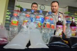 Kapolres Tasikmalaya Kota AKBP Febry Ma'ruf (kanan) menunjukkan sempel miras oplosan pada gelar perkara di Makopolres Tasikmalaya, Jawa Barat, Jumat (27/4/2018). Polres Tasikmalaya Kota mengamankan 800 botol miras jenis arak oplosan, 300 liter miras racikan yang dikemas botol plastik yang berasal dari wilayah Bandung untuk diedarkan ke wilayah Tasikmalaya dan berhasil mengamankan satu tersangka kurir. (ANTARA FOTO/Adeng Bustomi)