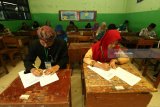 Sejumlah pelajar  berbusana adat tradisional mengikuti Ujian Sekolah Berstandar Nasional (USBN) di SMP Muhammadiyah 11 Surabaya, Jawa Timur, Sabtu (21/4). Kegiatan itu dalam rangka memperingati Hari Kartini. Antara Jatim/Didik Suhartono/zk/18