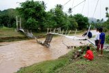 Sejumlah warga melihat kondisi jembatan gantung yang rusak akibat banjir di Desa Buhu, Kabupaten Gorontalo, Gorontalo, Selasa (17/4). Banjir yang terjadi akibat meluapnya sungai Alo tersebut merusak jembatan dan sejumlah rumah warga yang ada di enam desa di Kecamatan Tibawa.  (ANTARA FOTO/Adiwinata Solihin)